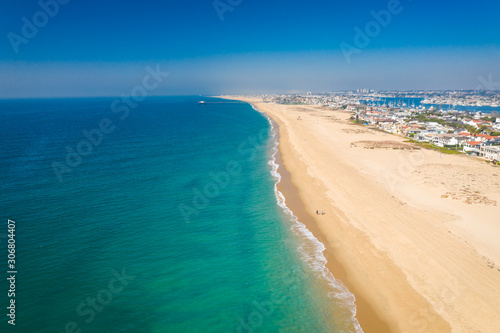 Aerial drone shot over Orange County, California with beach and sand below on a sunny Summer blue sky day.