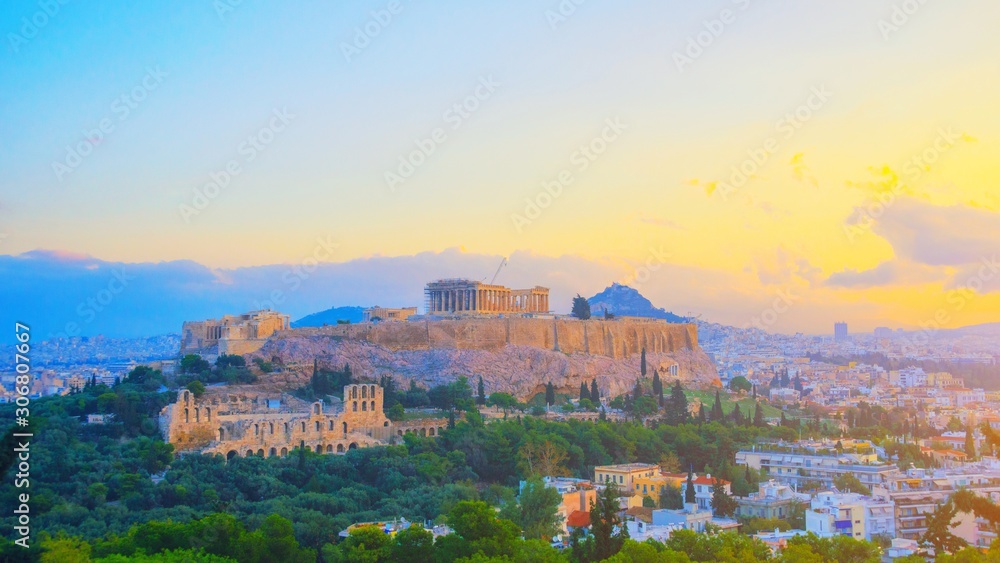 Parthenon temple in Acropolis Hill, Athens, Greece, shot in blue hour over old town during colorful sunset with pink and purple clouds in the sky. Lycabettus Hill on background panorama Europe travel.