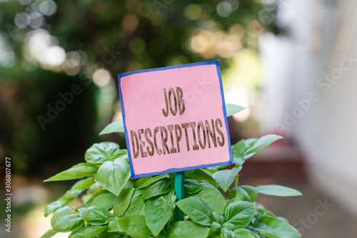 Writing note showing Job Descriptions. Business concept for a formal account of an employee s is responsibilities Plain paper attached to stick and placed in the grassy land © Artur