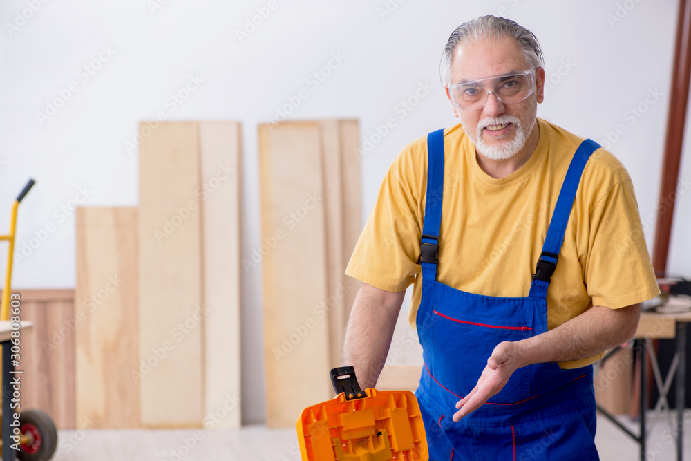 Old male carpenter working in workshop Old male carpenter working in workshop