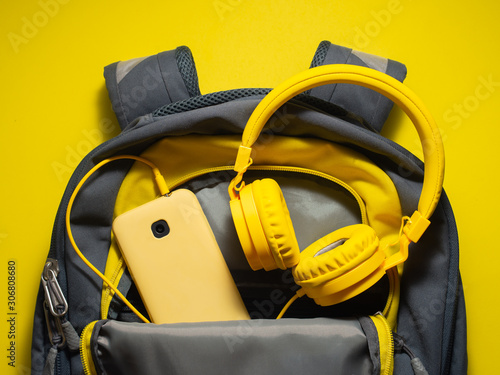 a pair of headphones and a smartphone inside an unzipped bag