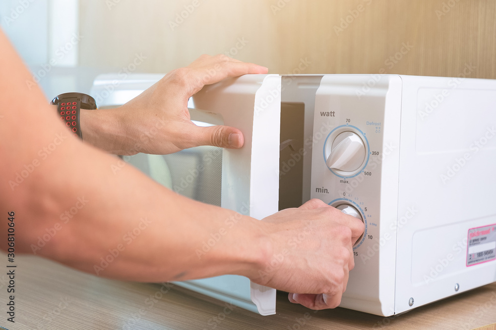 Woman's Hands Closing Microwave Oven Door And Preparing Food in microwave. Woman's Hands Closing Microwave Oven Door And Preparing Food in microwave.
