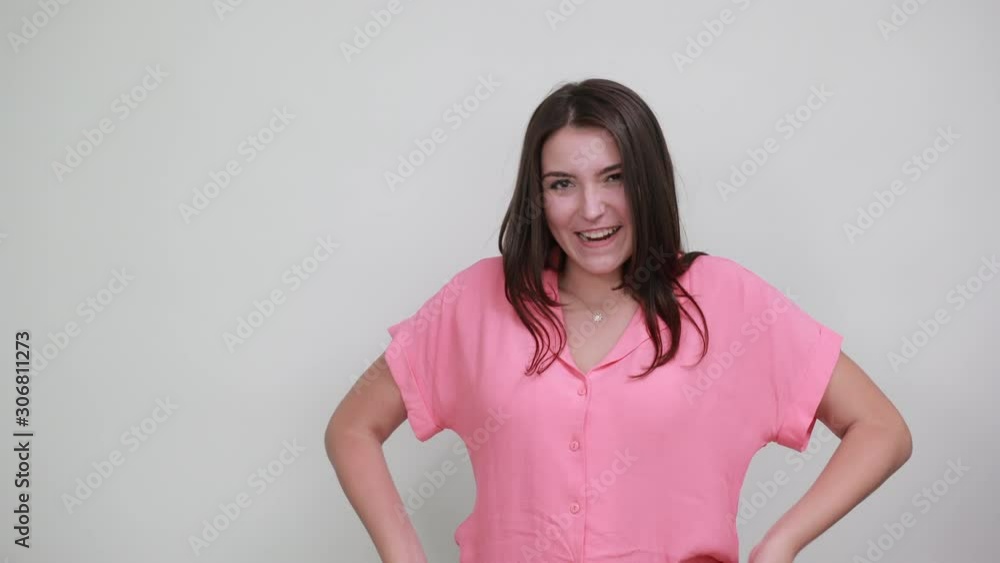 Funny caucasian young woman in pink shirt keeping hand on head, showing horns like cow isolated on white background in studio. People sincere emotions, lifestyle concept. Funny caucasian young woman in pink shirt keeping hand on head, showing horns like cow isolated on white background in studio. People sincere emotions, lifestyle concept.