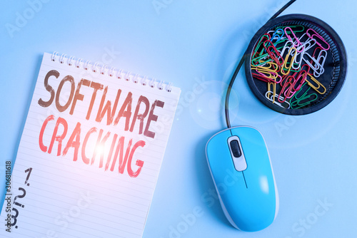 Word writing text Software Cracking. Business photo showcasing modification of software to remove or disable features Blank notebook and clips with computer mouse placed above pastel backdrop photo