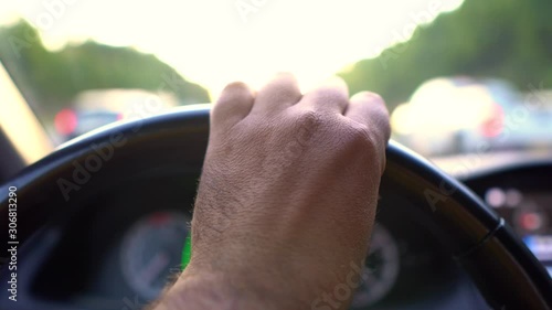 Wallpaper Mural Hand steering a cars steering wheel while other cars are passing by during rush hour in first person view Torontodigital.ca