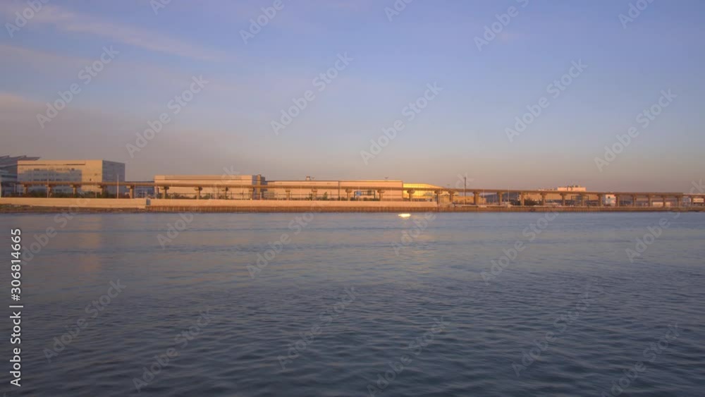 Tokyo,Japan-December 1, 2019: Tokyo Haneda international airport and Tokyo Monorail viewed from a boat crusing on Tokyo bay at sunset Tokyo,Japan-December 1, 2019: Tokyo Haneda international airport and Tokyo Monorail viewed from a boat crusing on Tokyo bay at sunset