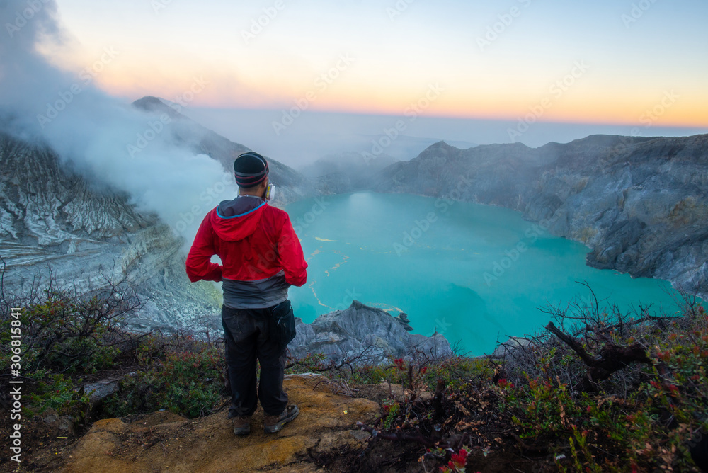 Tourist looking to Kawah Ijen volcano at dawn. Ijen volcano complex has some of the highest levels of sulfur one of the more dangerous places on Earth.