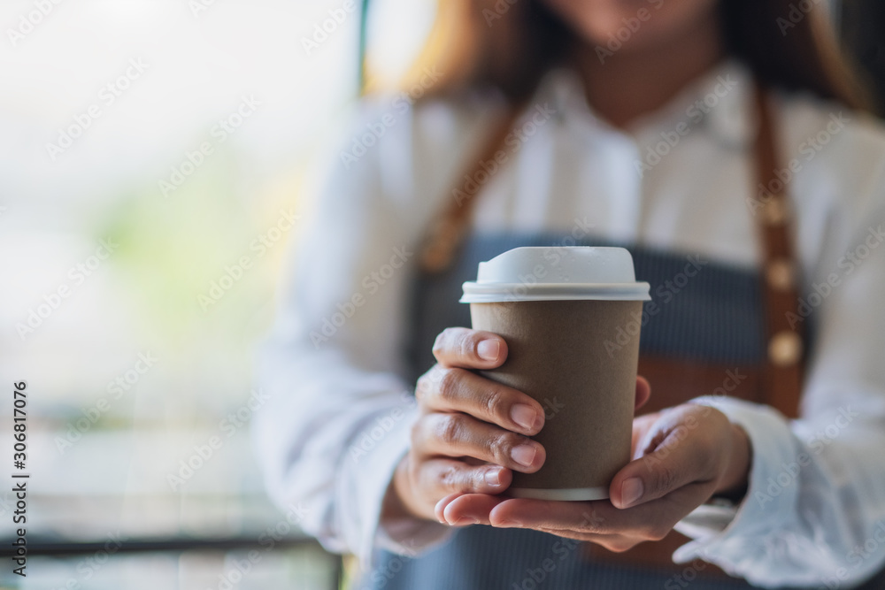 A waitress holding and serving a paper cup of hot coffee in cafe A waitress holding and serving a paper cup of hot coffee in cafe