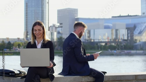 Financial specialist consulting her clients by video calling on laptop outdoors photo