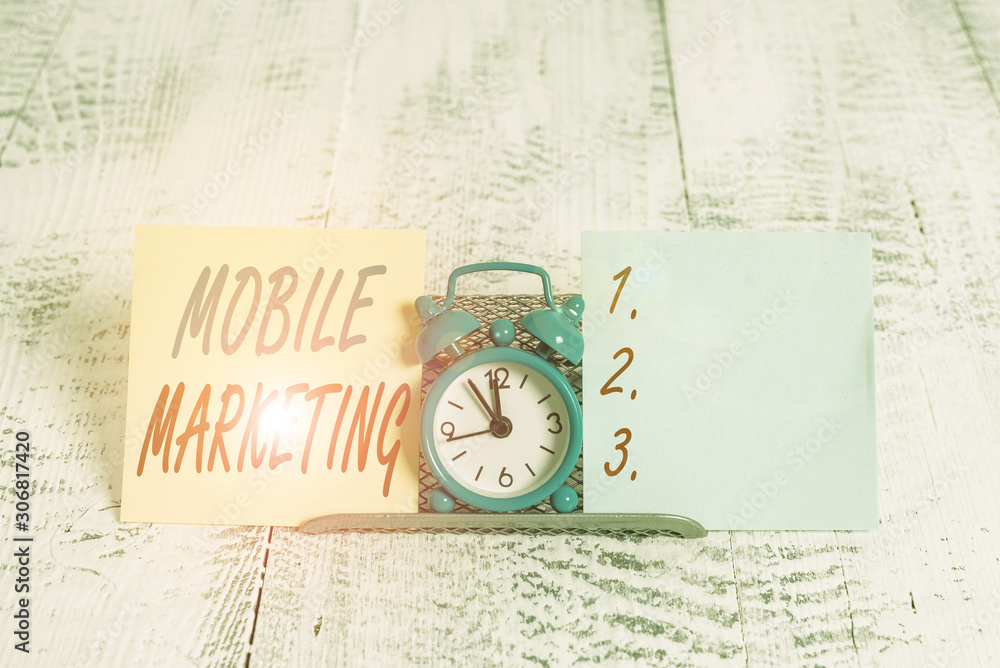 Conceptual hand writing showing Mobile Marketing. Concept meaning promotional activity designed for delivery to cell phones Mini blue clock standing above buffer wire between two paper