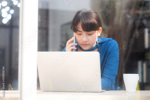Beautiful asian young businesswoman excited and glad of success work with laptop, girl taking mobile smart phone and working coffee shop, career freelance business concept.