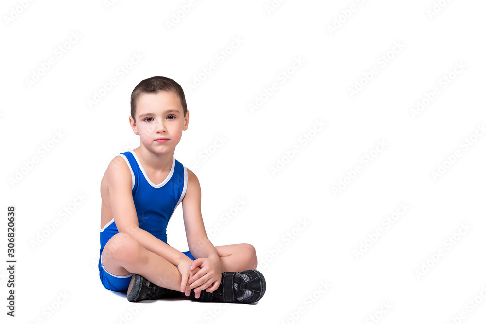 Sporty cheerful boy in a blue wrestling tights is ready to engage in sports exercises, is sitting on the floor on a white isolated background Sporty cheerful boy in a blue wrestling tights is ready to engage in sports exercises, is sitting on the floor on a white isolated background