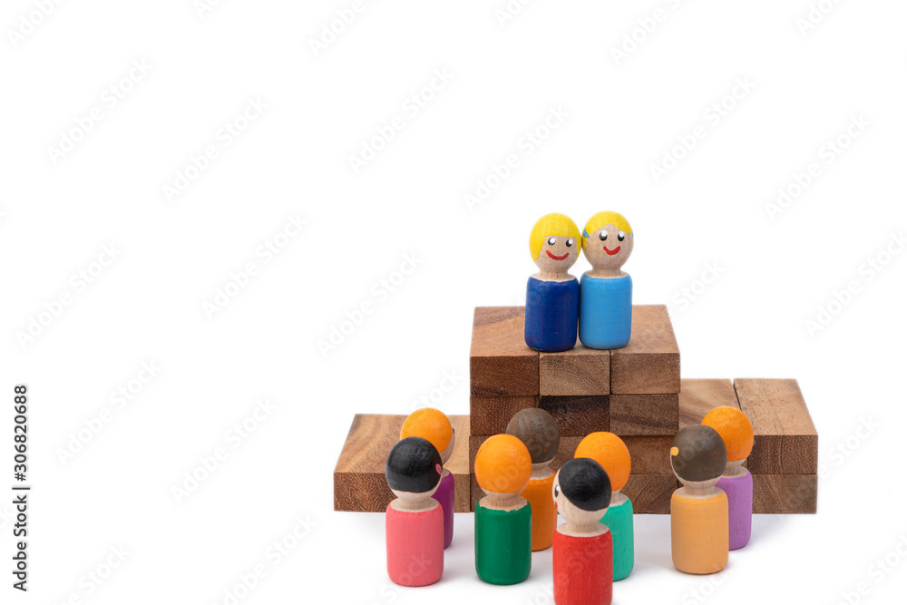 A wooden toy man stands on stairs and looks out at a large number of people who obey her. The concept of the ruling man and the dictator. Images of the population and the president A wooden toy man stands on stairs and looks out at a large number of people who obey her. The concept of the ruling man and the dictator. Images of the population and the president