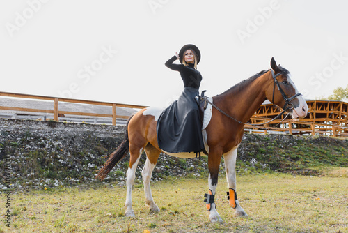 Happy fashionable young woman posing with a horse on the beach © Serhii
