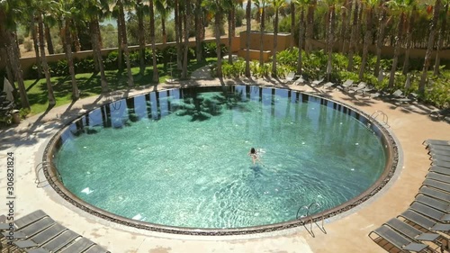 view from the top as young woman swims on circular pool photo