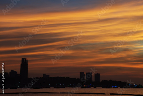 Colorful twilight cloud over a city silhouette and sea in an evening