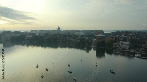 Aerial, boats on calm lake in front of city on gloomy morning, tilt up photo