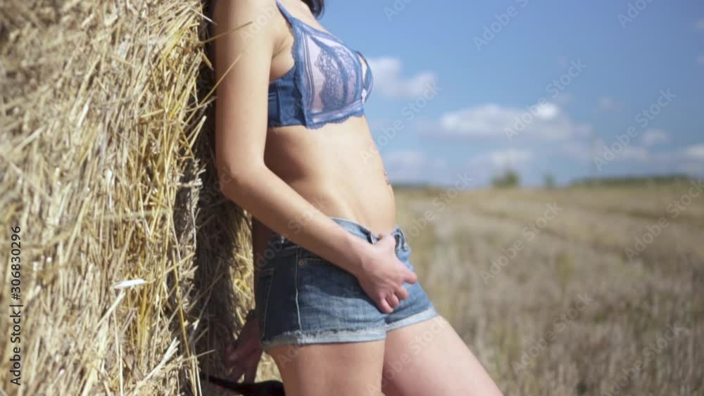Slow motion of a sexy woman wearing high heels leaning on a hay bale. PARALLAX LOWERING Slow motion of a sexy woman wearing high heels leaning on a hay bale. PARALLAX LOWERING