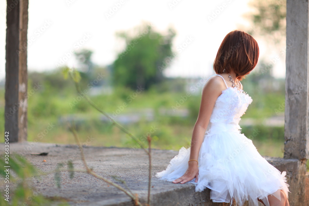 Portrait of thoughtful young bride in a white wedding dress sitting alone near the
field and enjoys the moment Portrait of thoughtful young bride in a white wedding dress sitting alone near the
field and enjoys the moment
