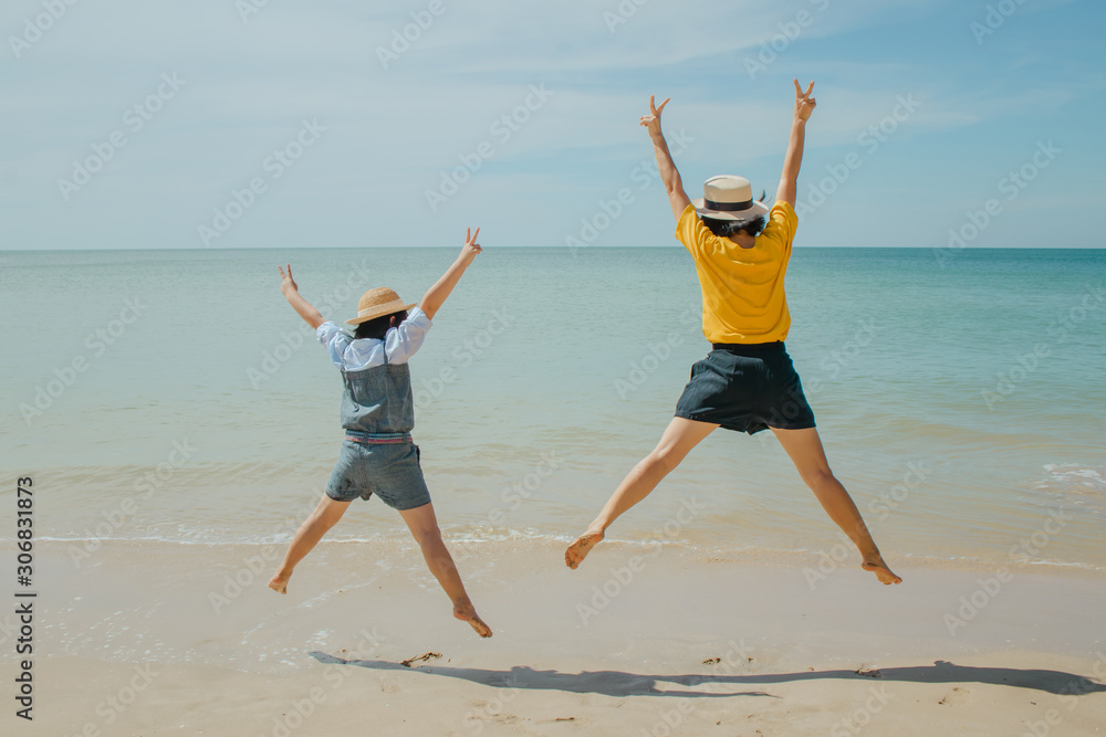 Obraz premium Summer Vacation and Travel Trip Concept : Woman and child felling happiness, they jumping on sand beach.