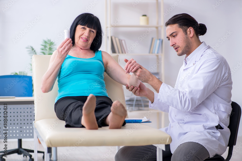 Fototapeta premium Young male doctor examining old female patient
