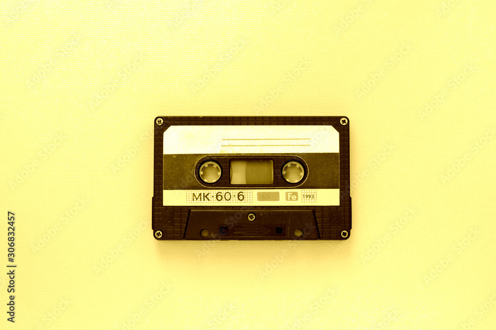 Old audio tape cassette, top view. Old technology concept. Yellow color toned