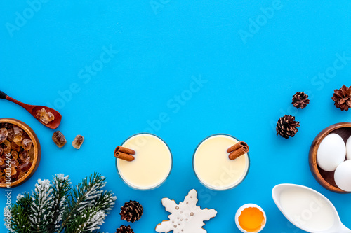 Ingredients for New Year drink eggnog - eggs, milk, cinnamon on blue background top view frame copy space