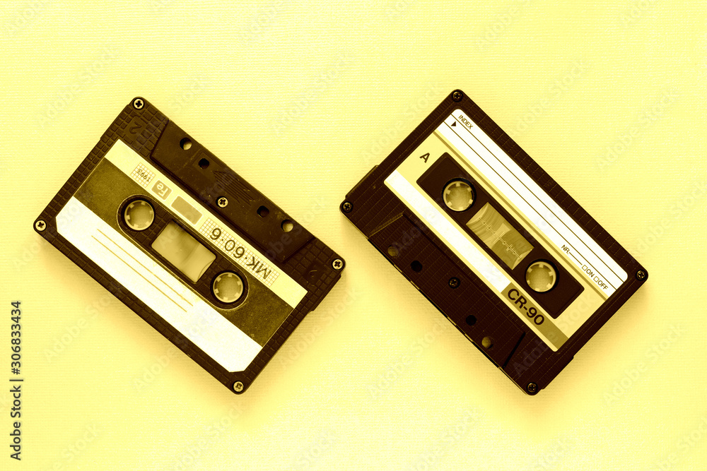 Fototapeta premium Two audio tape cassettes, top view. Old technology concept. Yellow color toned