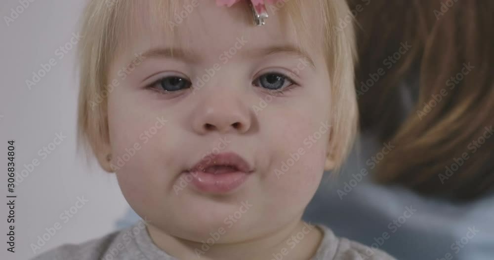 Side view of pretty Caucasian baby girl chewing cookie. Portrait of beautiful child with grey eyes and blond hair. Cinema 4k ProRes HQ. Side view of pretty Caucasian baby girl chewing cookie. Portrait of beautiful child with grey eyes and blond hair. Cinema 4k ProRes HQ.