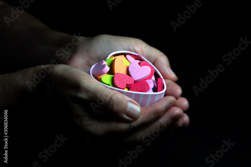 Wallpaper Mural Colorful hearts in hands on black background, love concept Torontodigital.ca