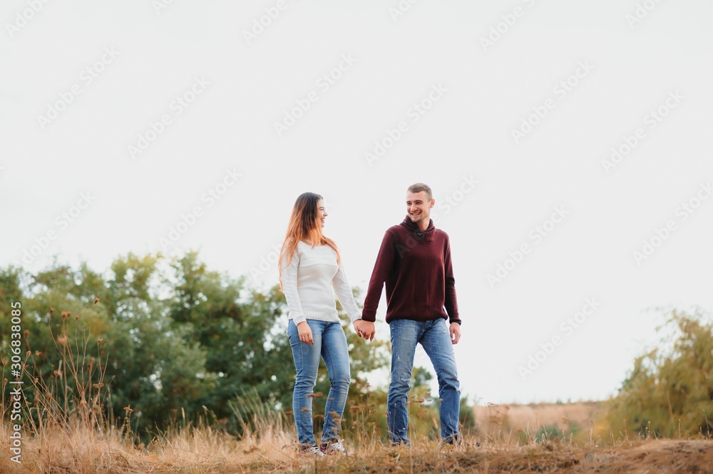Beautiful young couple walking in autumn park.