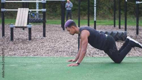 dolly shot going around a muscular guy who does knee push ups in an outdoor callisthenics sports park