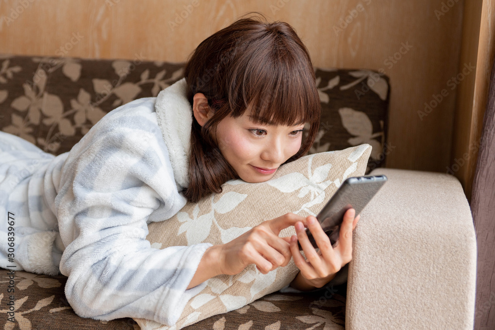 寝転んで携帯電話を持ってる女性