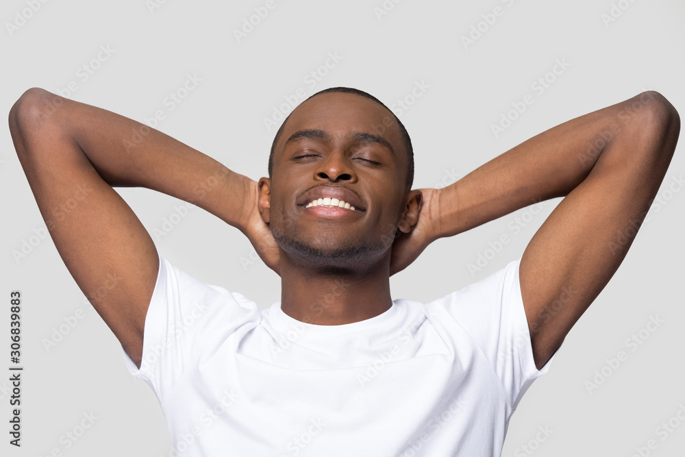 Smiling calm African American man relaxing with hands behind head Smiling calm African American man relaxing with hands behind head