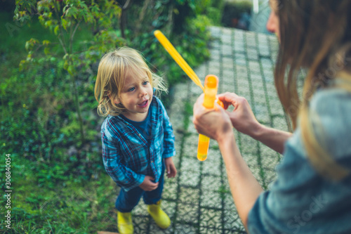 Toddler blowing bubble swith his mother in garden