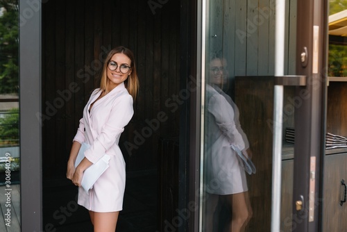 Portrait of a successful businesswoman holding a digital tablet pad and a folder while proudly standing near office.