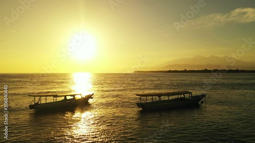 Two long fishing traditional balinese boats bathing in the golden sun rays. tropical ocean with islands, summer holiday concept photo