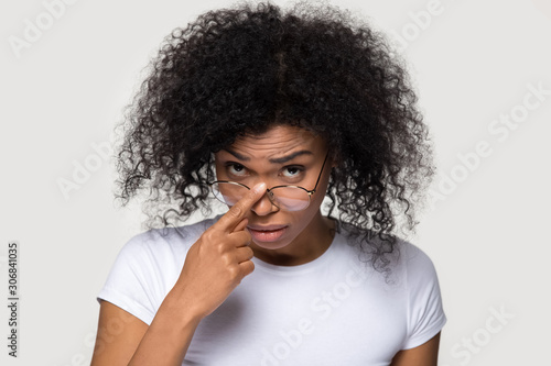 Doubtful African American woman taking off glasses, looking with disbelief photo