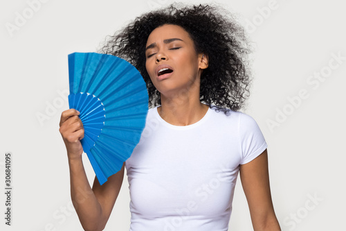 Tired African American woman suffering from heat, waving fan photo