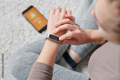 Hands of young active woman with smartwatch sitting on the floor