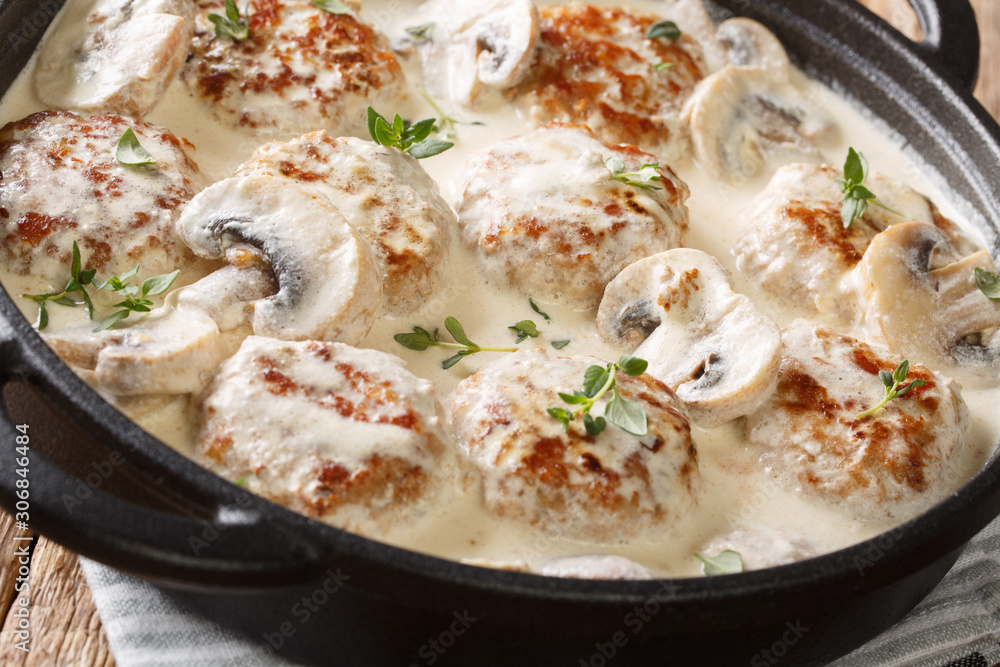 Tasty meatballs with mushrooms served in a creamy sauce with thyme close-up in a pan on the table. horizontal Tasty meatballs with mushrooms served in a creamy sauce with thyme close-up in a pan on the table. horizontal