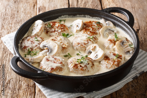 Serving of meatballs with mushrooms in a creamy cheese sauce close-up in a pan on the table. horizontal