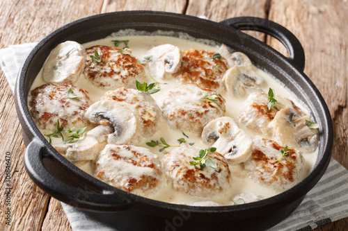 Homemade meatballs cooked with mushrooms served in a creamy sauce with thyme closeup in a pan. horizontal