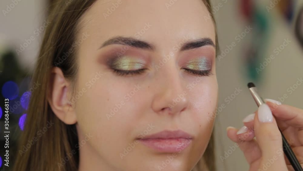 Professional makeup artist puts eye shadow on a client of a beauty salon. Professional makeup artist puts eye shadow on a client of a beauty salon.