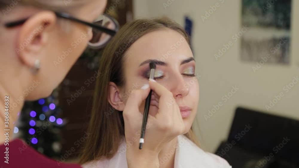 Professional makeup artist puts eye shadow on a client of a beauty salon. Professional makeup artist puts eye shadow on a client of a beauty salon.