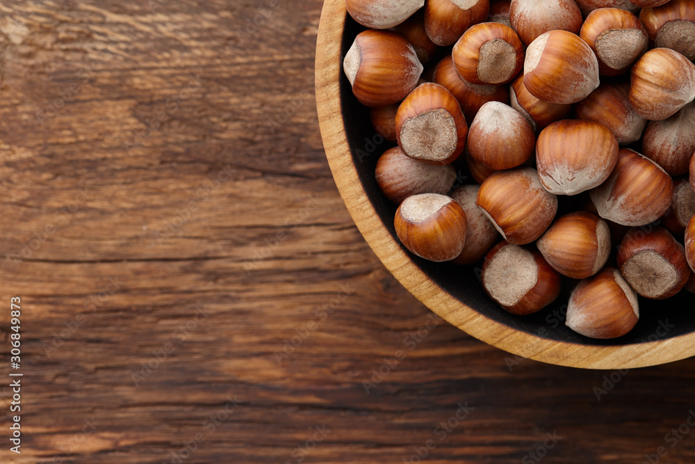 Hazelnuts in wooden bowl on textured background Hazelnuts in wooden bowl on textured background