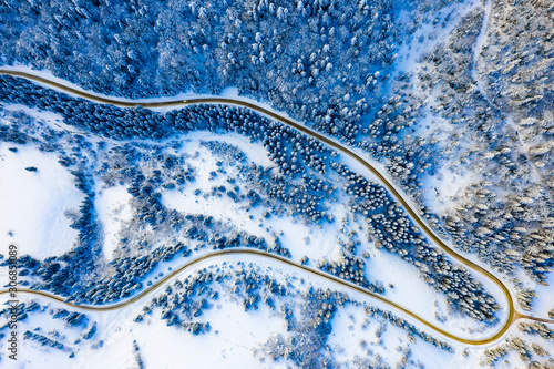 Travelling along winter forest in mountains, aerial landscape. Snowy weather concept
