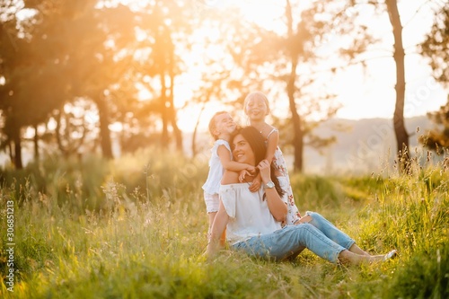 Mother and two daughters having fun in the park. Happiness and harmony in family life. Beauty nature scene with family outdoor lifestyle.