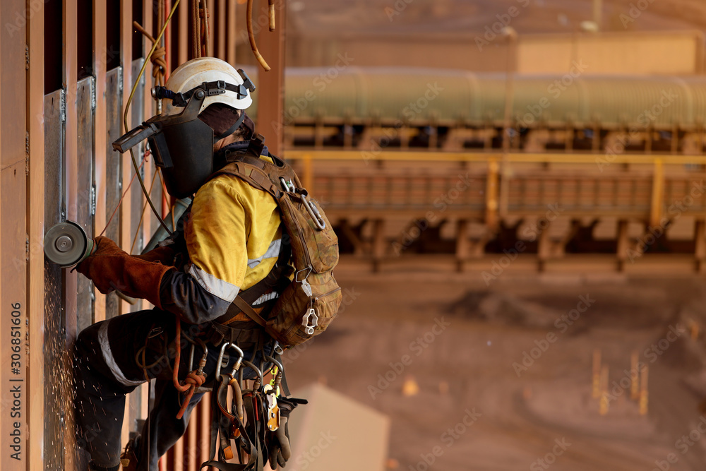 Side view of rope access technician welder services wearing white