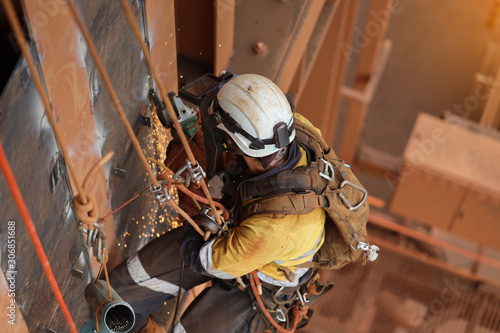 Εκτύπωση καμβά Tope view of rope access technician welder services using power grinder working